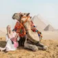 Tourists enjoying camel trekking at sunset near the Great Pyramids of Giza in Egypt.