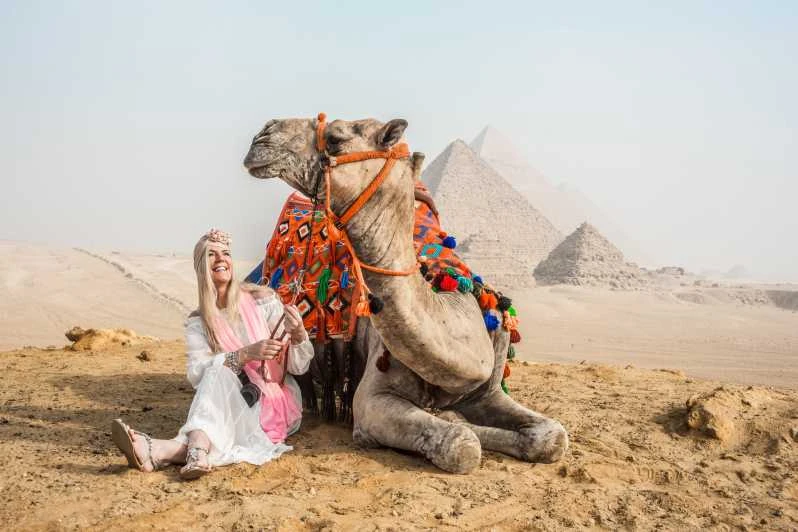 Tourists enjoying camel trekking at sunset near the Great Pyramids of Giza in Egypt.