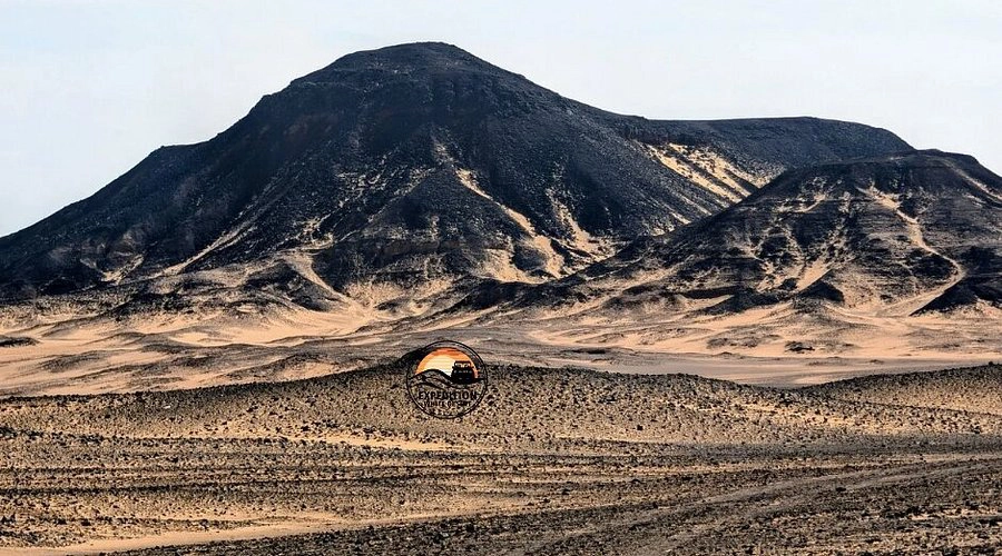 Backpack with hiking shoes, water bottles, sunscreen, and camera, prepared for exploring the Black Desert on a Heart Egypt Tours guided trip.