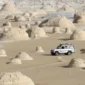 Traveler taking photos at Egypt’s White Desert with surreal rock formations and golden sunset