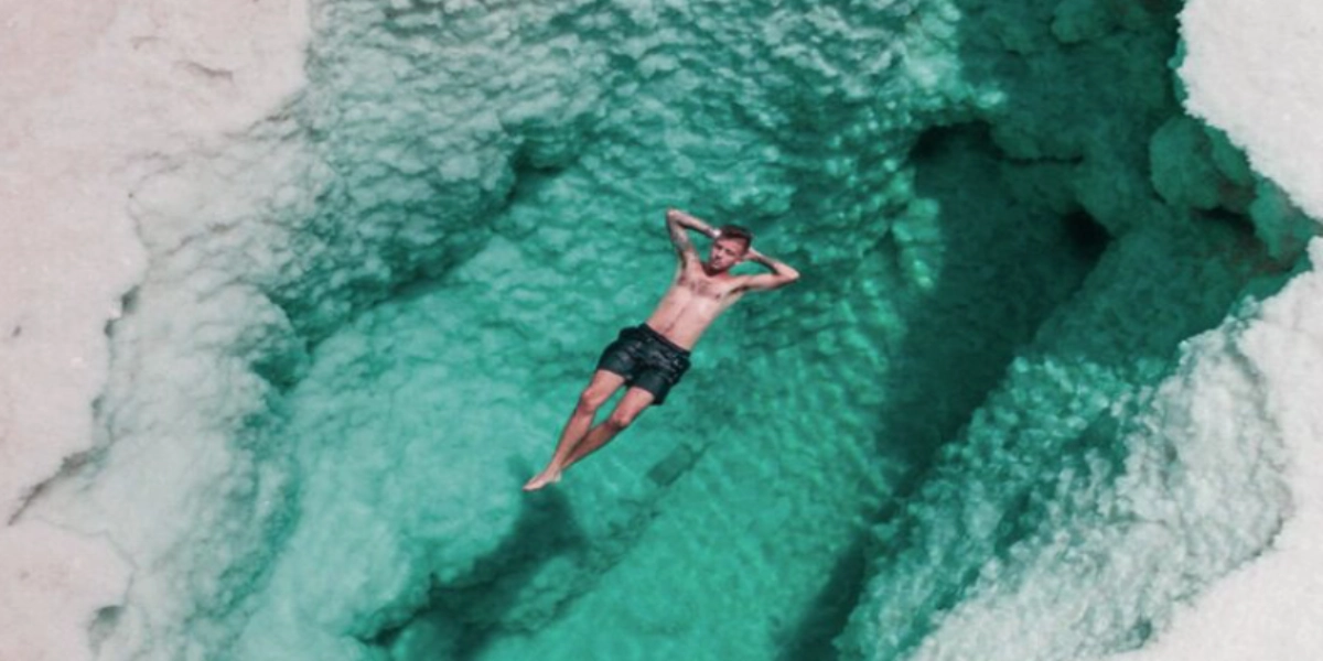 Sunset view over Siwa Oasis salt flats and natural hot springs, with travelers exploring and relaxing during a Heart Egypt Tours trip.